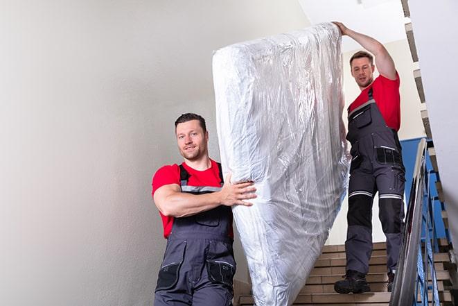 workers transporting a box spring out of a building in Cupertino, CA